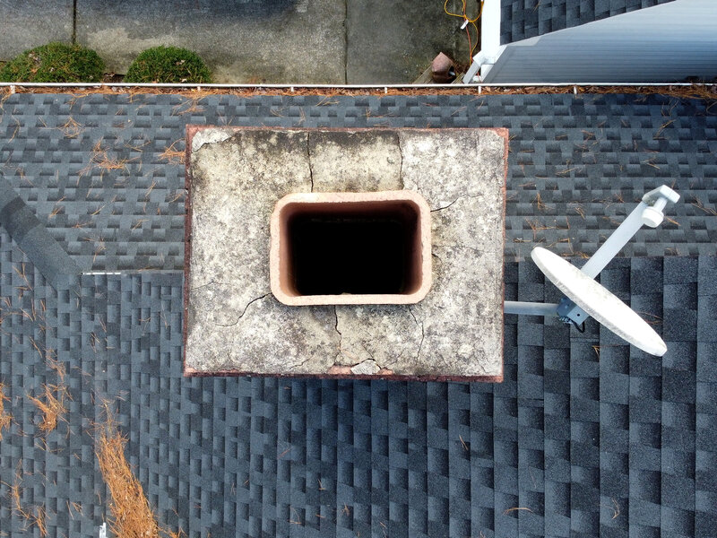 Top-down view of a cracked chimney crown and open flue tile