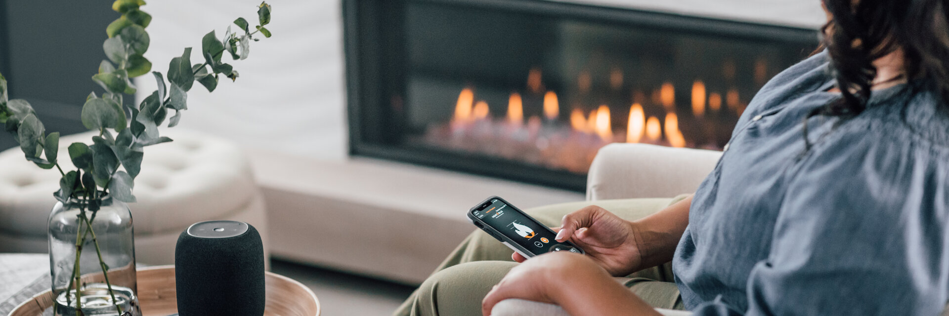 Indianapolis homeowner browsing fireplaces on her phone next to a modern linear fireplace