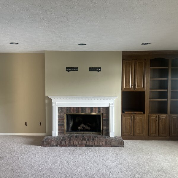Before—dated white-painted federal brick fireplace with stained-wood arched built-ins