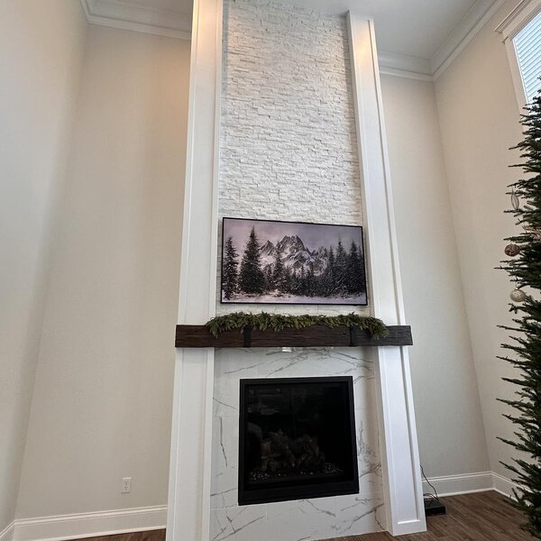 After—floor-to-ceiling vertical stone column with shiplap reveal pillars, dark wood mantel, gas firebox, and mounted TV